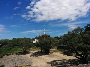 A lighthouse behind a beach and trees