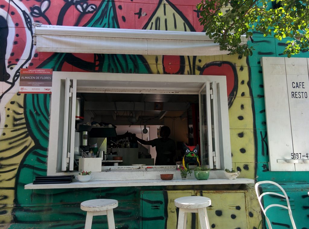 A window of the restaurant Almacen de Flores in Tigre. The wall is painted in many colors.