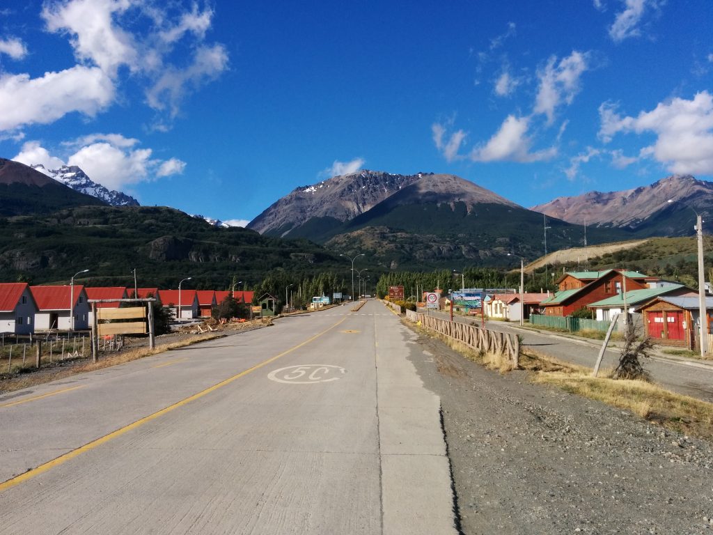 A road crossing a town with mountains in the background