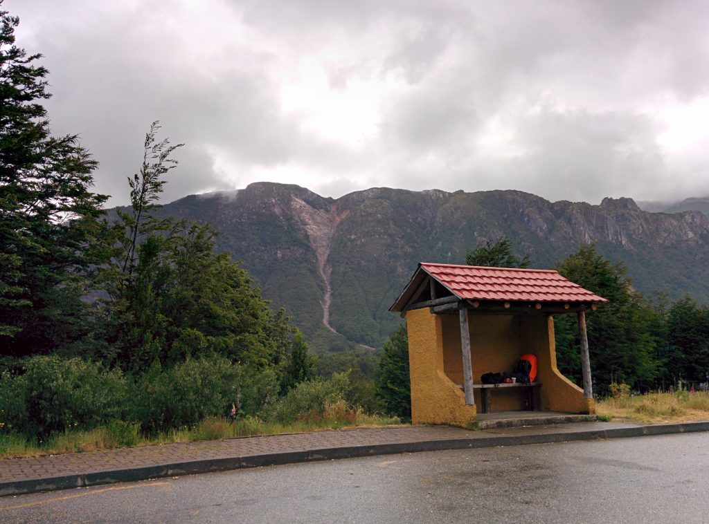 A bus stop aside a road with mountains in the background