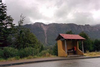 A bus stop aside a road with mountains in the background