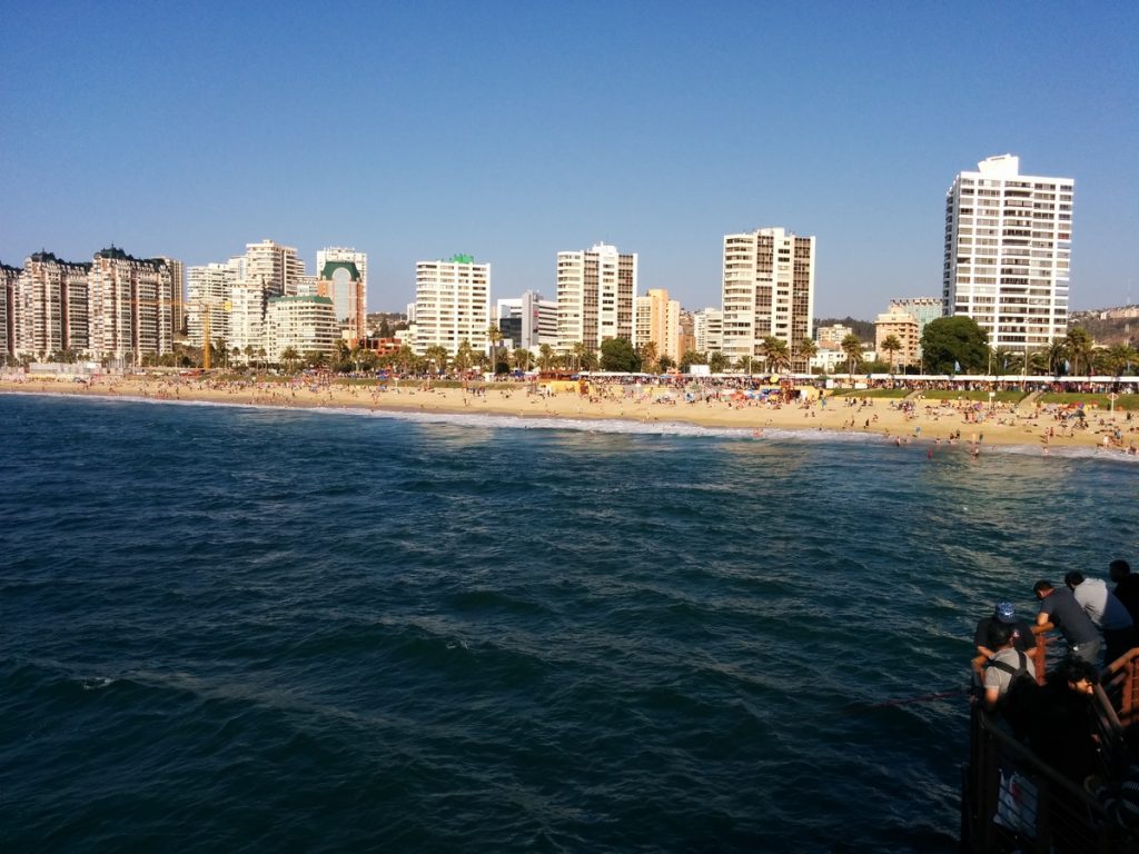 The sea and the beach in the froground and the city in the background.