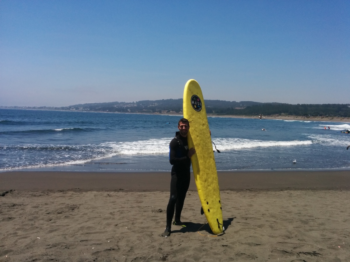Me in front of the sea on the beach with my yellow board.