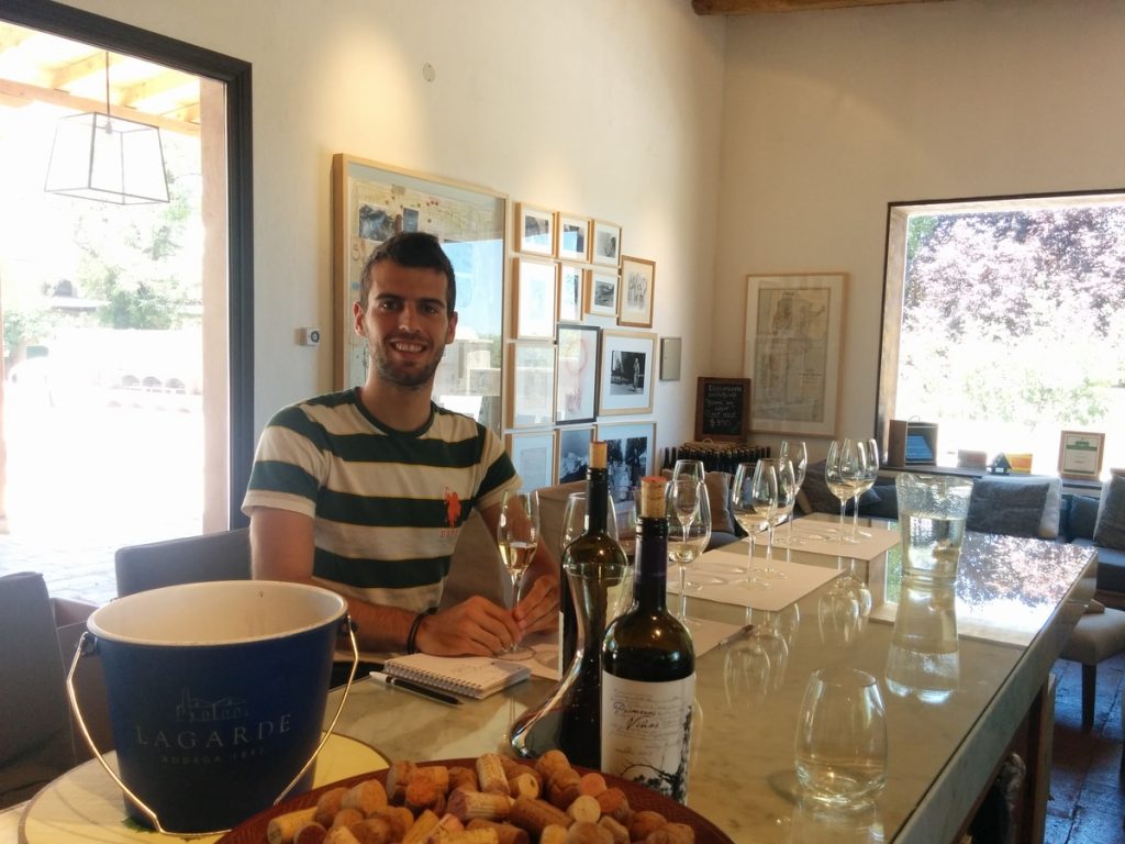 A man in front of tabla doing a wine tasting.