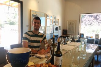 A man in front of tabla doing a wine tasting.