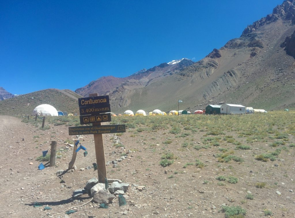 A signal saying Confluencia with tents behind